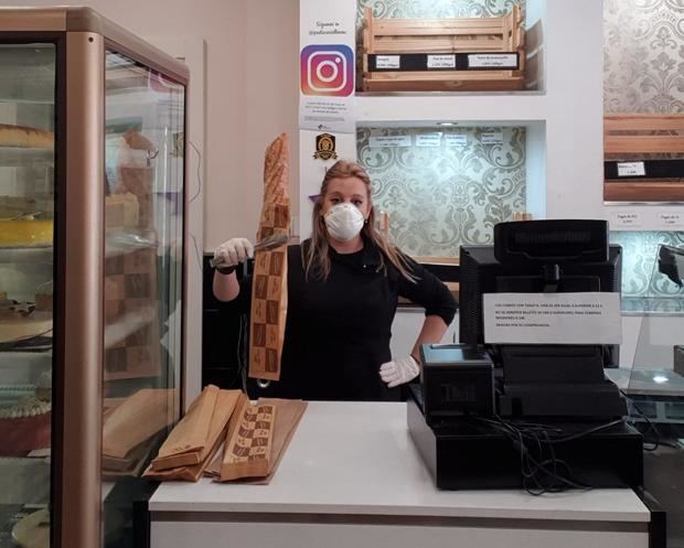 Cristina Espín tras el mostrador de su pastelería, con mascarilla, guantes y pinzas para los alimentos, son algunas de las medidas excepcionales que han adoptado para poder atender a los clientes ante la alerta sanitaria del Covid-19